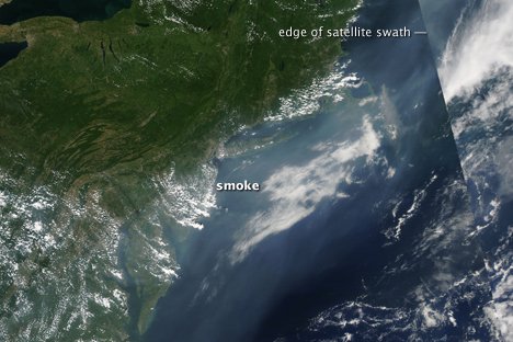 The image shows the transport of smoke from forest fires in Idaho and Montana across the United States and over the Atlantic Ocean. The haze is gray _ white and is smooth in texture compared to clouds.